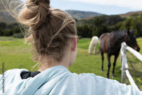 Teenage girl watching horses in a field photo