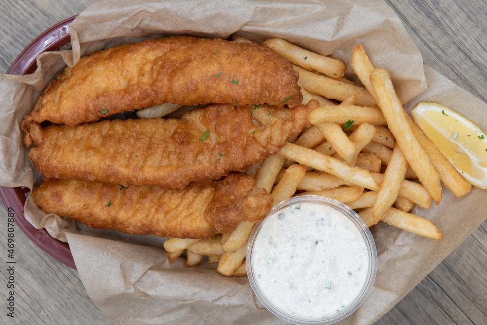Overhead view of crispy order of breaded fish sticks combined in the basket with french fries to satisfy a hearty appetite Overhead view of crispy order of breaded fish sticks combined in the basket with french fries to satisfy a hearty appetite