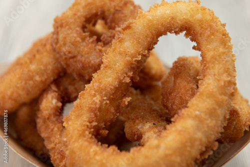 Close up of texture of crispy side order of onion rings contained in a cardboard boat to eat on the go