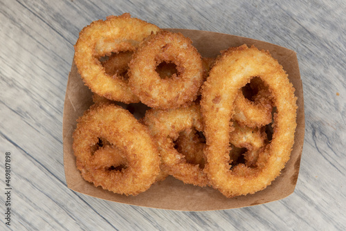 Overhead view of crispy side order of onion rings contained in a cardboard boat to eat on the go