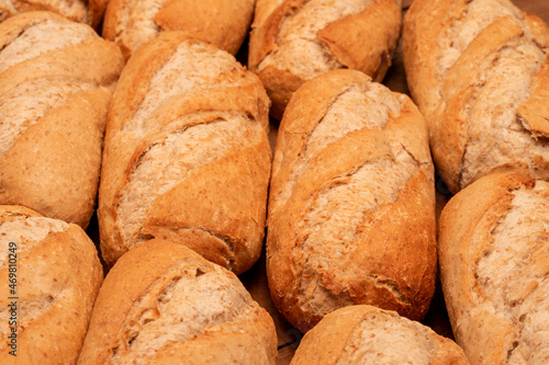 CLOSE UP OF ARTISAN WHOLEMEAL BREAD ROLLS FRESHLY MADE IN THE BAKERY.