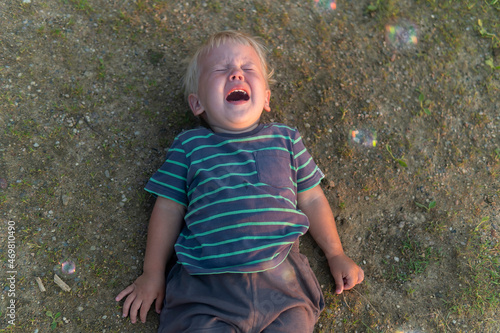 Фотография a little boy lies on the ground and cries a lot