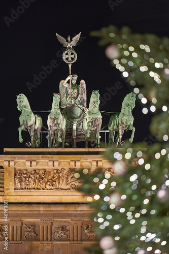 Germany Berlin, Christmas tree in front of illuminated Brandenburg Gate in Berlin City in the evening with dark sky , close up 