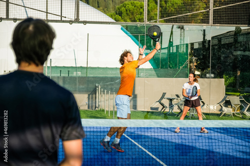 Mixed padel match in a blue grass padel court - .Beautiful girl and handsome man playing padel outdoor © damianobuffo