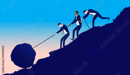 Fotografia Team working hard - Determined businessmen pulling heavy rock up hill