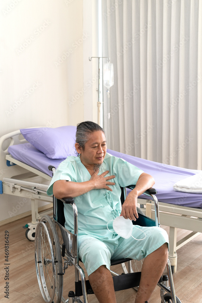 An elderly Asian male patient puts his hands on his chest because of