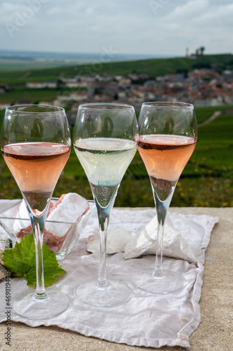 Glasses of white and rose brut champagne wine and examples of vineyard soils  white chalk stones and firestones and view on grand cru vineyards of  Montagne de Reims near Verzenay  Champagne  France