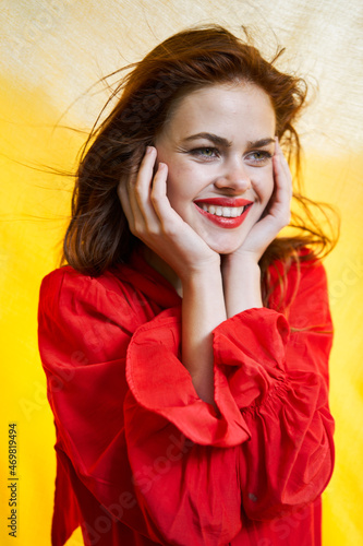 smiling woman in red dress posing yellow background