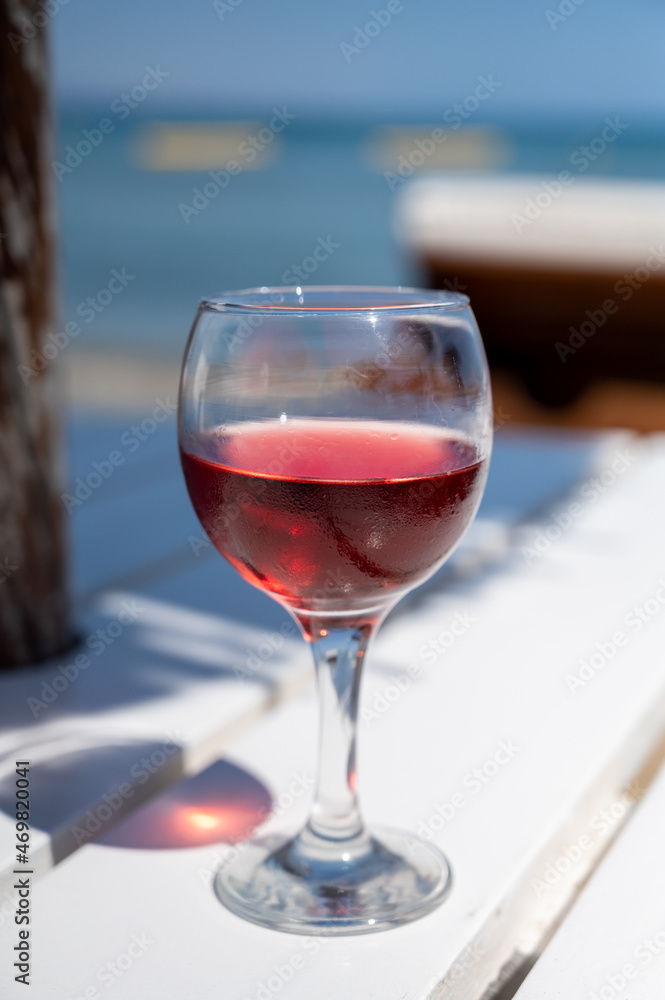 Drinking of cold rose wine in lounge bar on sunny sandy beach with blue sea water on background