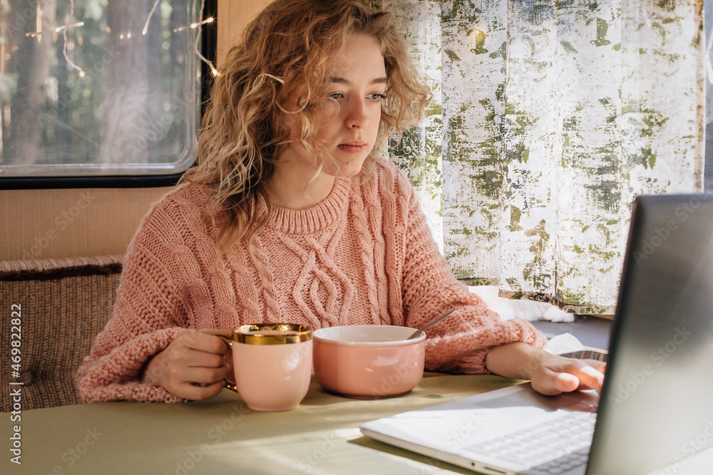 Woman in trailer eating breakfast at laptop. Woman in trailer eating breakfast at laptop.