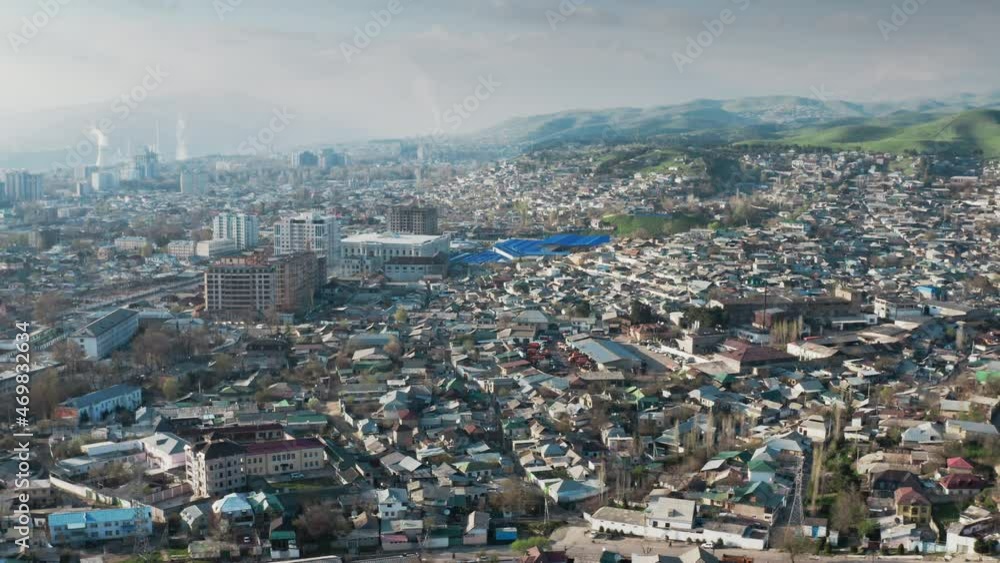 Aerial urban landscape of the city is a spring sunny day. Area of city with small houses from a bird's-eye view, in the distance you can see green plains and mountains in fog. Dushanbe. Tajikistan. Aerial urban landscape of the city is a spring sunny day. Area of city with small houses from a bird's-eye view, in the distance you can see green plains and mountains in fog. Dushanbe. Tajikistan.