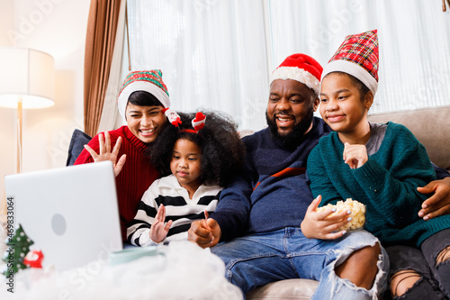 African American family have fun during video call on laptop and sitting together on the sofa at home. cheerful young family with children laughing. African American family in Christmas theme