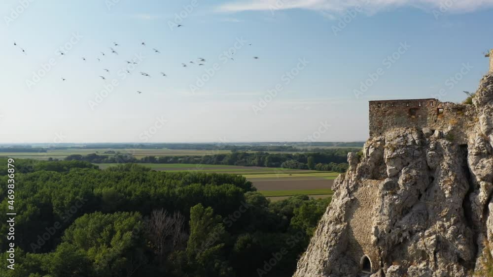 Rotating side angle drone shot of the Hrad Devin castle with birds flying around the cliffs Rotating side angle drone shot of the Hrad Devin castle with birds flying around the cliffs