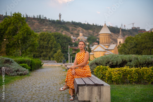 a woman is sitting on a bench in tbilisi photo