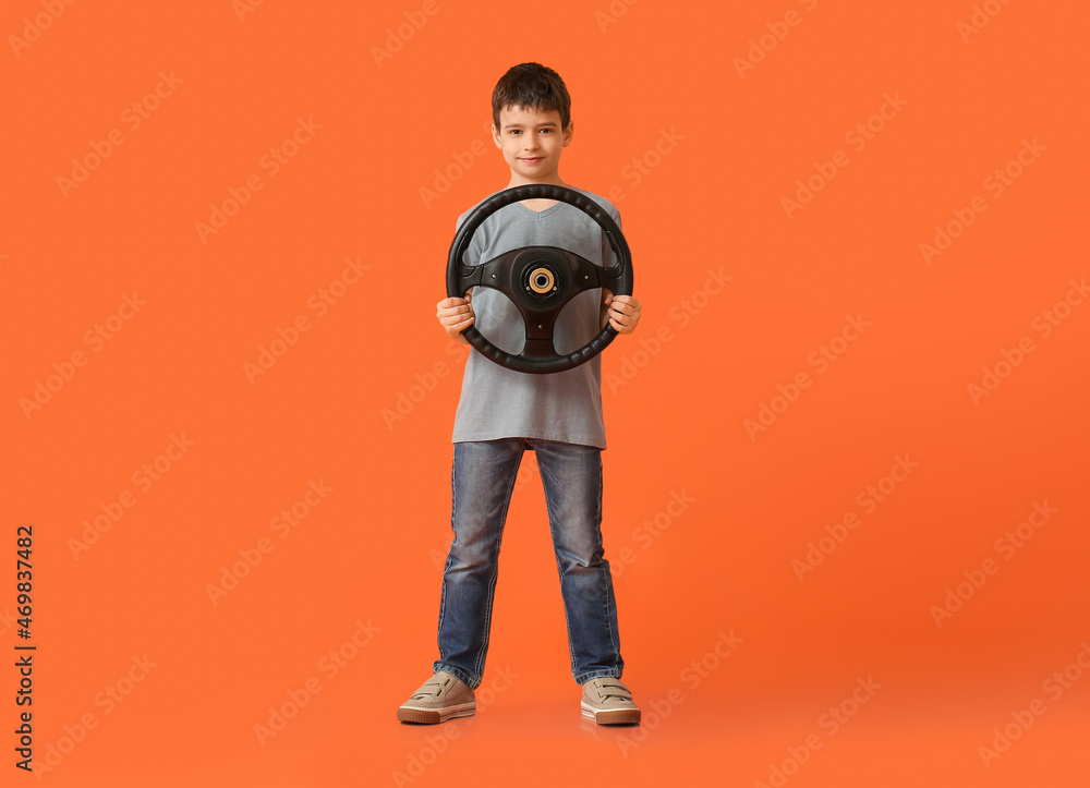 Little boy with steering wheel on color background Little boy with steering wheel on color background