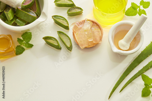 Aloe vera extract research in laboratory with yellow water in petri dish and a beaker mortar and pestle ,  green leaf in white background for aloe vera advertising , research content , top view  photo