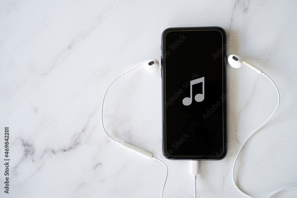 Obraz premium Mobile Phone with Music Note on Screen and Headphones - Concept Music on Your Phone with Copy Space