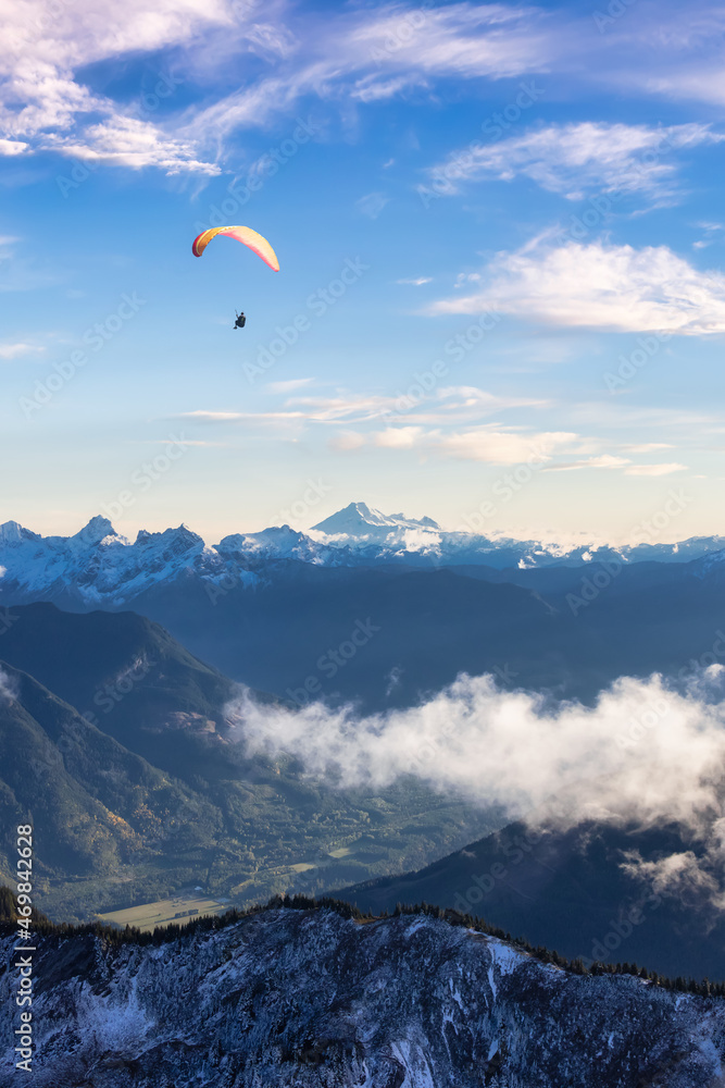 Aerial View of Canadian Rocky Mountains with snow on top. Paraglider flying Adventure Composition. Colorful Sunset Sky Art Render. Nature Landscape near Chilliwack, East of Vancouver, BC, Canada. Aerial View of Canadian Rocky Mountains with snow on top. Paraglider flying Adventure Composition. Colorful Sunset Sky Art Render. Nature Landscape near Chilliwack, East of Vancouver, BC, Canada.