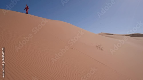 Sand boarding The Desert Dunes in Dubai While Wearing a Costume - Static Wide Shot photo