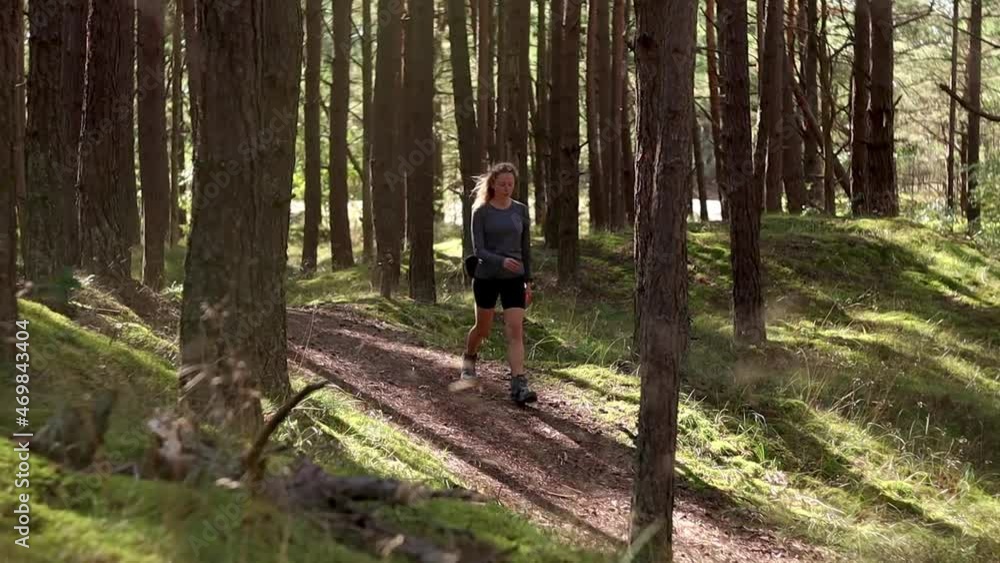 Girl Walking a Forest Trail. Hiking in a Pine Tree Forest in sunlight. Going on a hike, walk, exploring Latvian outdoors in summer. Life in the country, rural living. Girl Walking a Forest Trail. Hiking in a Pine Tree Forest in sunlight. Going on a hike, walk, exploring Latvian outdoors in summer. Life in the country, rural living.