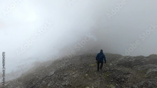 Wallpaper Mural A mountaineer is walking down a rock into the clouds at a very high altitude. You can see snow on the left and the abyss on the right side. Torontodigital.ca