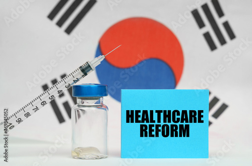 Vaccine, syringe and blue plate with the inscription - HEALTHCARE REFORM. In the background the flag of South Korea