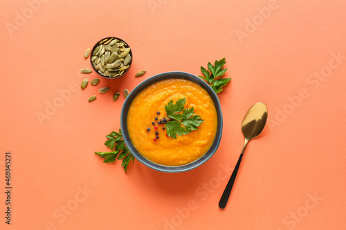 Tableau sur toile Bowl with delicious pumpkin cream soup and seeds on color background