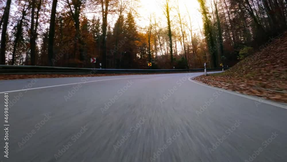 Hyperlapse of driving fast down a curvy road in a autumnal forest with a low standing sun and oncoming traffic from a lower car drivers front view. Hyperlapse of driving fast down a curvy road in a autumnal forest with a low standing sun and oncoming traffic from a lower car drivers front view.