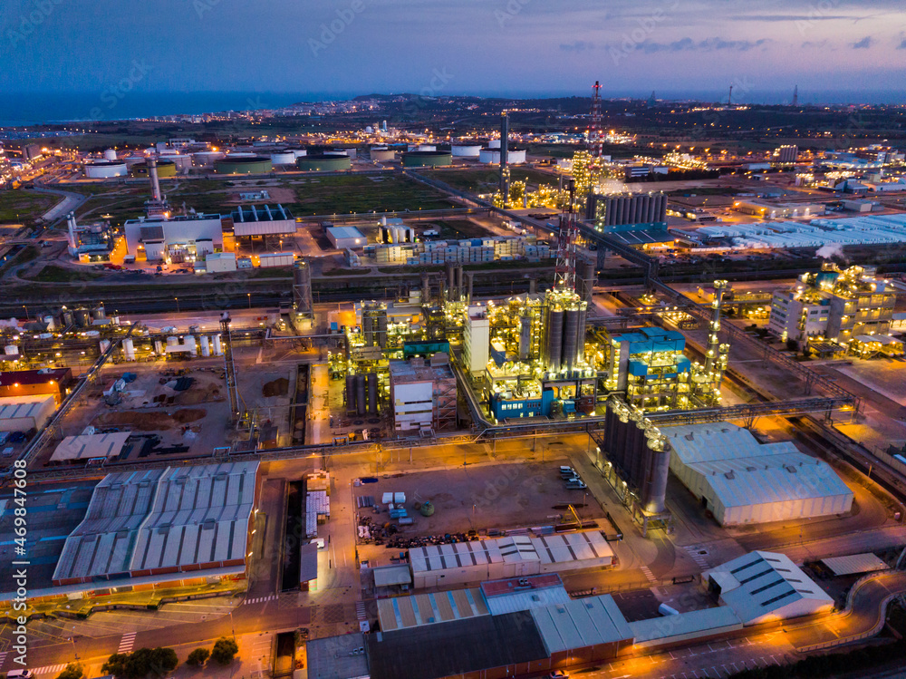 Obraz premium Aerial view of illuminated chemical process plant near Spanish town of Salou at twilight