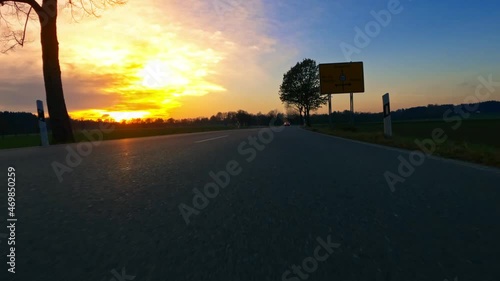 Driving into the sunset. Low front view of a car which is cruising over the asphalt at an orange sunset. photo