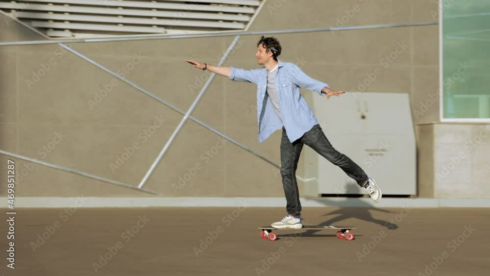 Man riding longboard perform tricks on skateboard in urban street skatepark. Casual hipster guy wearing jeans shirt and bandana skateboarding. Leisure activity, sport extreme, city lifestyle concept Man riding longboard perform tricks on skateboard in urban street skatepark. Casual hipster guy wearing jeans shirt and bandana skateboarding. Leisure activity, sport extreme, city lifestyle concept