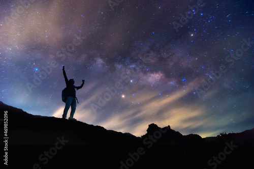 Landscape with Milky Way. Night sky with stars and silhouette of a standing happy man on the mountain  Success or winner  leader concept. High iso with Noise.