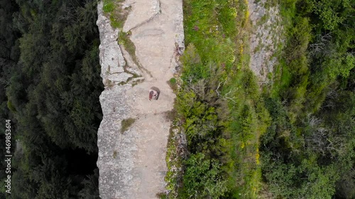 Aerial: zenital shot of a man with a suitcase walking on a clif photo