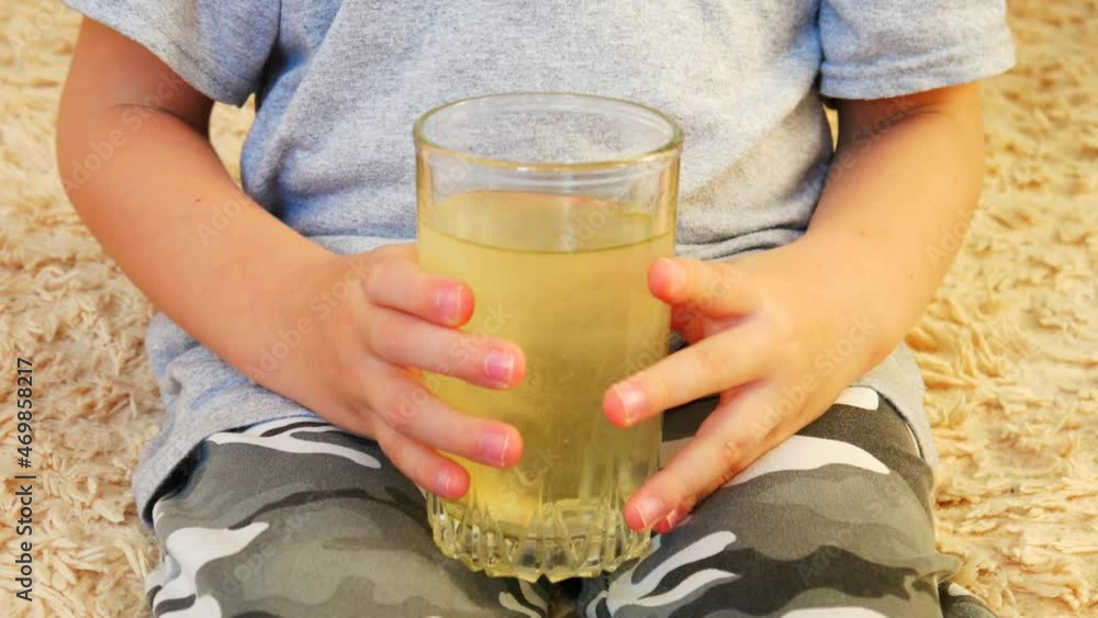 Close-up of the hands of a little boy holding a glass of water and dipping a dissolving pill into it Close-up of the hands of a little boy holding a glass of water and dipping a dissolving pill into it