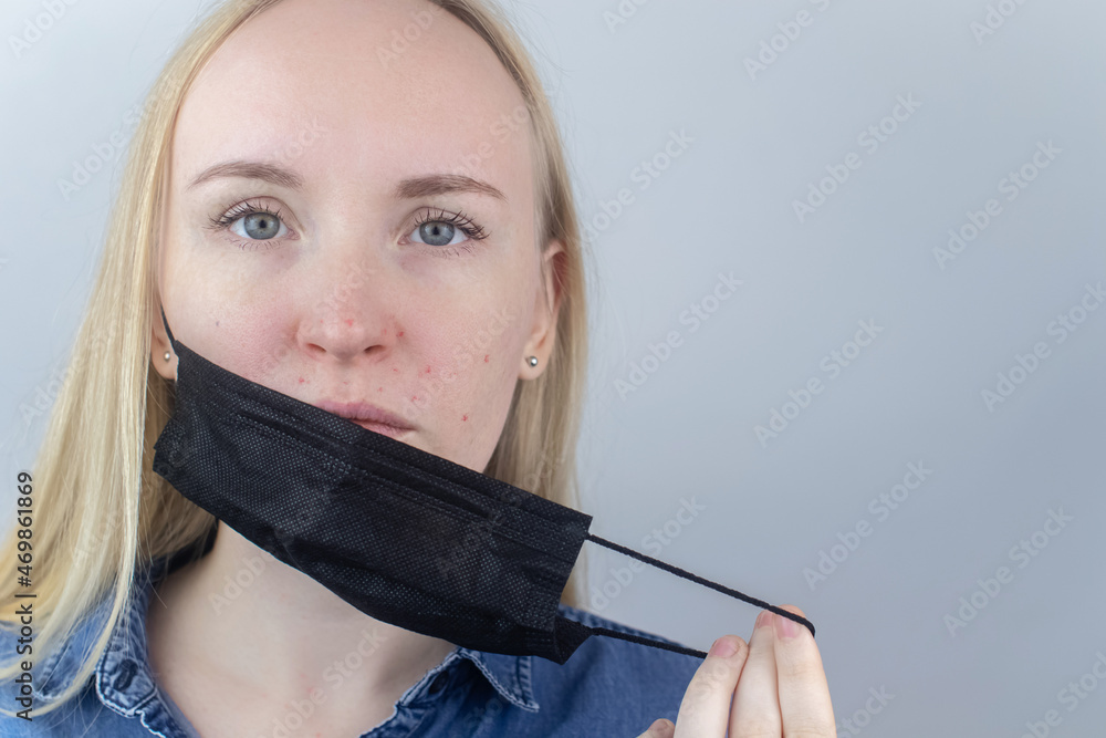 Foto Stock Woman removes the protective mask and shows irritation on