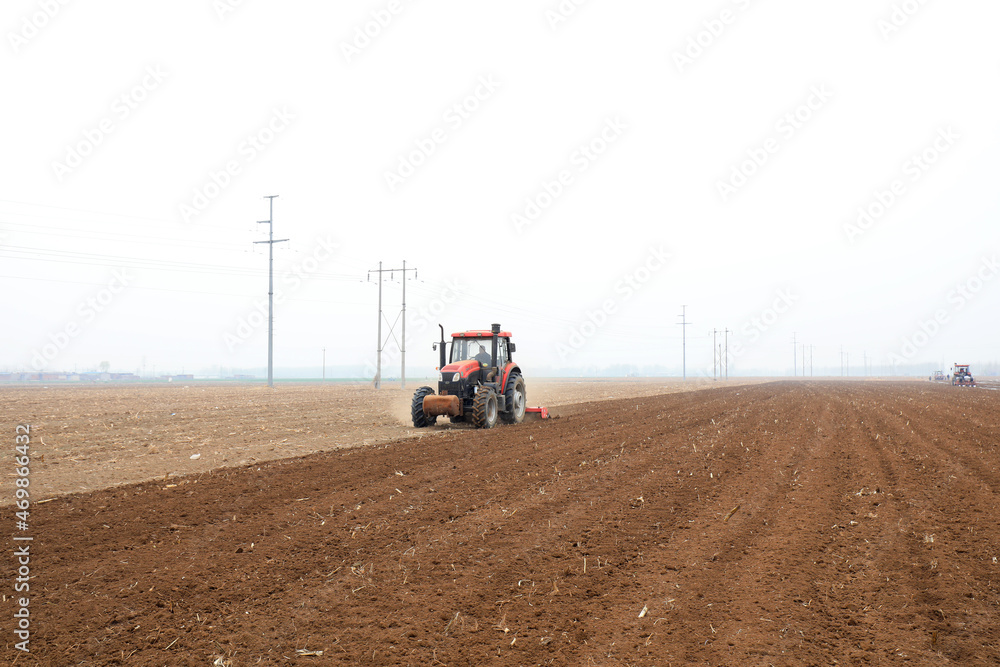 Obraz premium Farmers drive tractors to level up the land for planting corn on the farm.