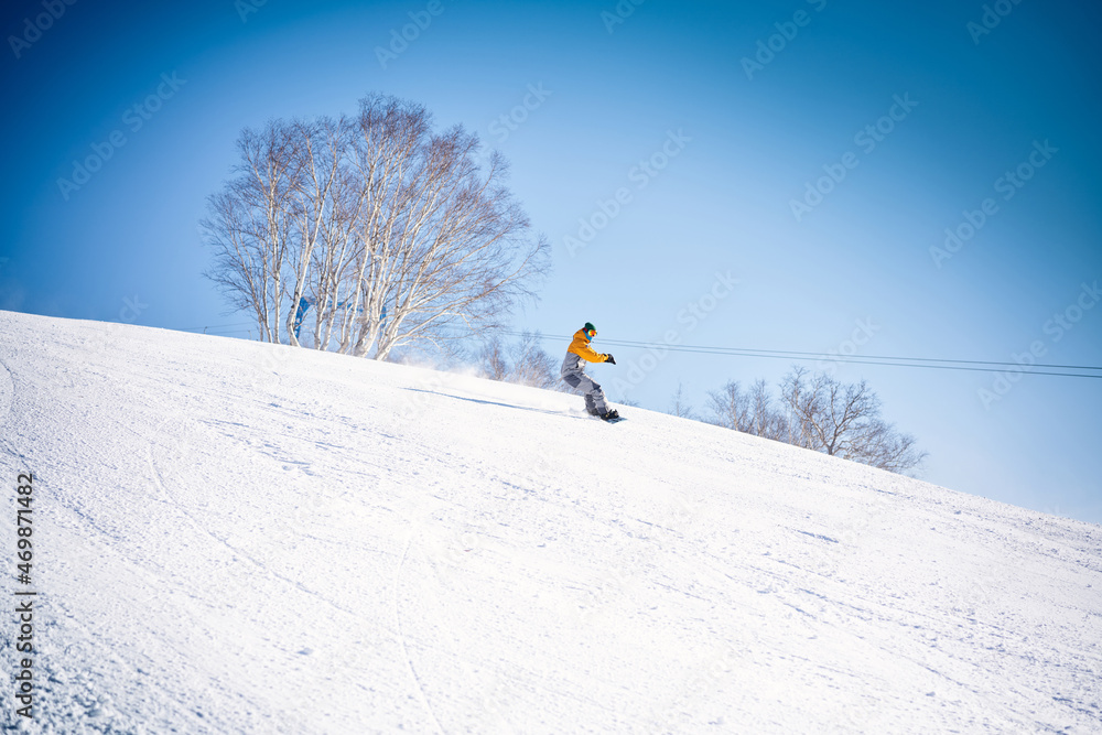 Snowboarder riding down the hill in front of blue sky