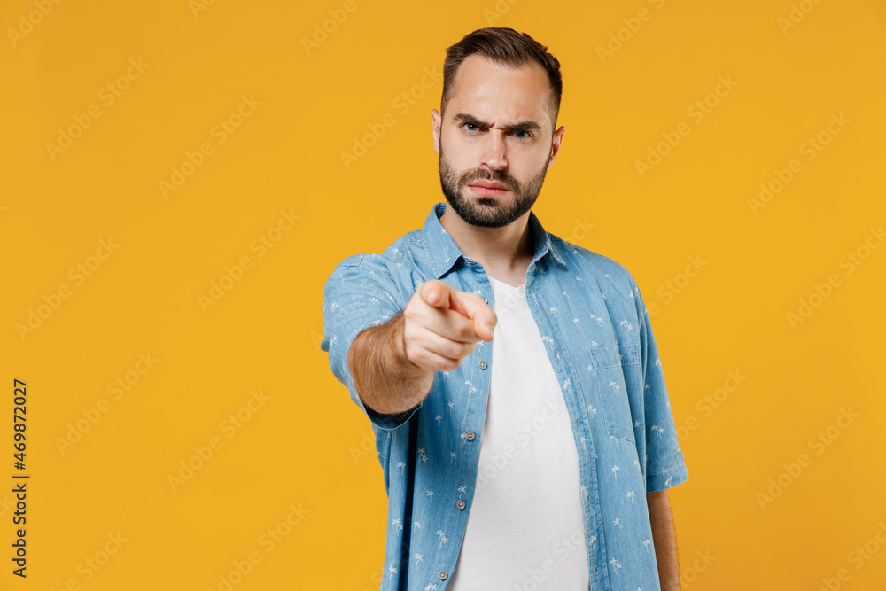 Young sad serious indignant caucasian man 20s wearing blue shirt white t-shirt point index finger camera on you say do it isolated on plain yellow background studio portrait. People lifestyle concept. Young sad serious indignant caucasian man 20s wearing blue shirt white t-shirt point index finger camera on you say do it isolated on plain yellow background studio portrait. People lifestyle concept.
