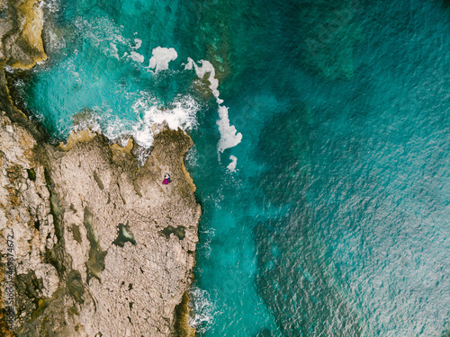 Man and woman are hugging each other on the rocks near the blue sea. Top view