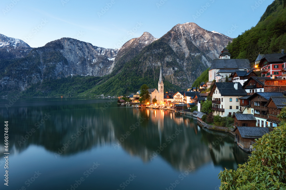 Fototapeta premium Classic postcard view of famous Hallstatt lakeside town reflecting in Hallstattersee lake in the Austrian Alps in scenic morning light on a beautiful sunny day in summer, Salzkammergut region, Austria