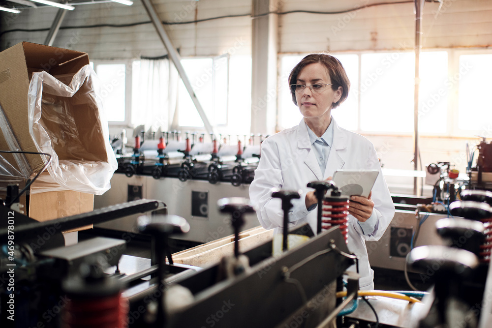 Female executive working at factory with machines Female executive working at factory with machines