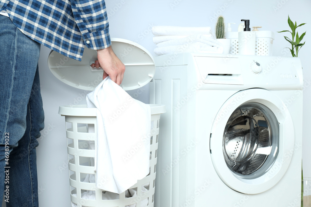 Concept of housework with washing machine and guy on white background Concept of housework with washing machine and guy on white background