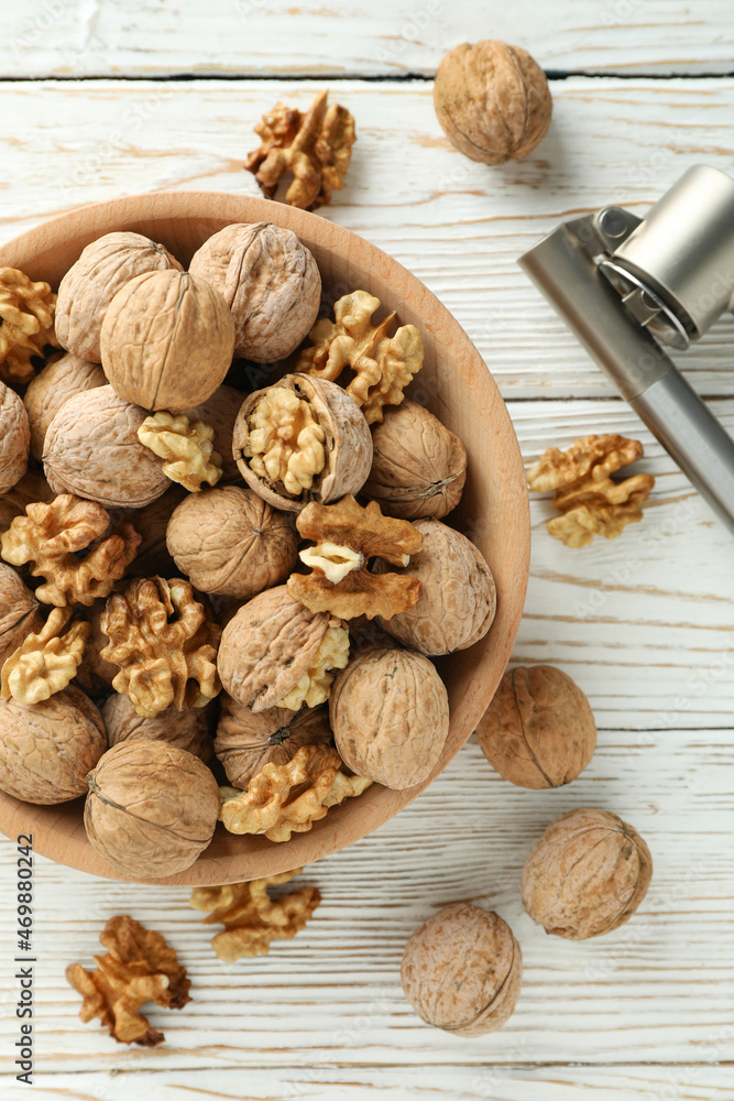 Nutcracker and bowl of walnuts on white wooden background Nutcracker and bowl of walnuts on white wooden background