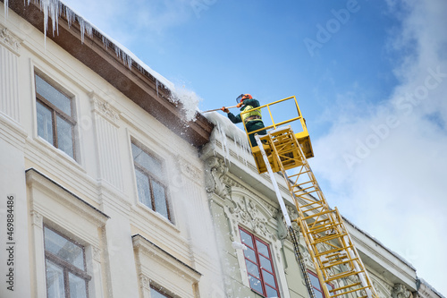 Public utilities on special vehicles remove icicles from the roofs of houses on the Rynok square in Lviv. Roof Winter Workers. photo