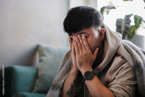 Ill man on sofa with hands covering face