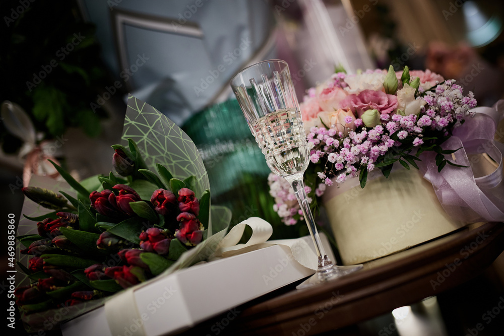 Obraz premium On the table are bouquets of flowers and glasses of champagne on the background of gifts.