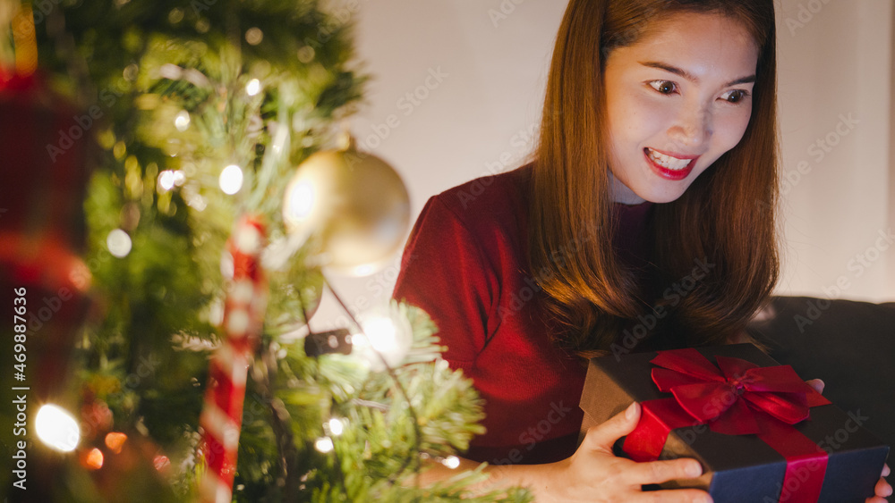 Young Asia female using tablet video call talking with couple with X'Mas present box, Christmas tree decorated with ornament in living room at home. Christmas night and New Year holiday festival. Young Asia female using tablet video call talking with couple with X'Mas present box, Christmas tree decorated with ornament in living room at home. Christmas night and New Year holiday festival.