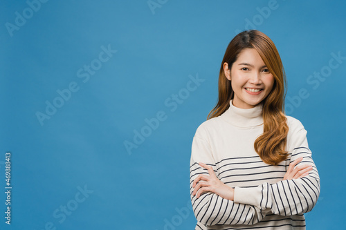 Obraz na plátně Portrait of young Asia lady with positive expression, arms crossed, smile broadly, dressed in casual clothing and looking at camera over blue background