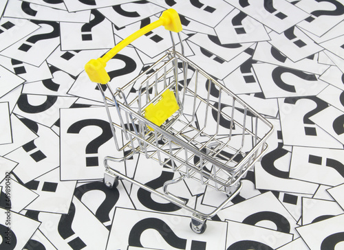 Shopping trolley on question marks background. Shopping questions concept. 