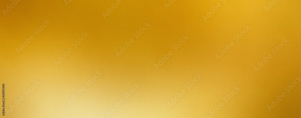 Gold wall texture background. Yellow shiny gold foil paint on wall surface with light reflection Gold wall texture background. Yellow shiny gold foil paint on wall surface with light reflection